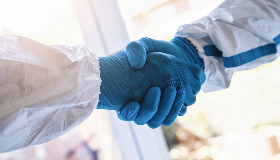Technicien en combinaison de protection intégrale blanche avec masque respiratoire effectue la désinfection d'un rebord de fenêtre dans un intérieur résidentiel moderne