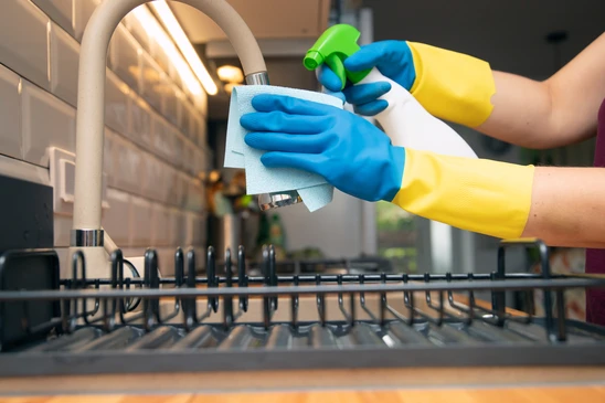 Technicien en uniforme professionnel et gilet de sécurité, dans un local professionnel (bureau, couloir ou zone commune), effectuant une intervention de maintenance générale sur un équipement (radiateur, climatiseur, ou accès à une installation technique en hauteur). L'image doit montrer une action concrète de maintenance multidisciplinaire, distincte du nettoyage au sol ou de la vitrerie.